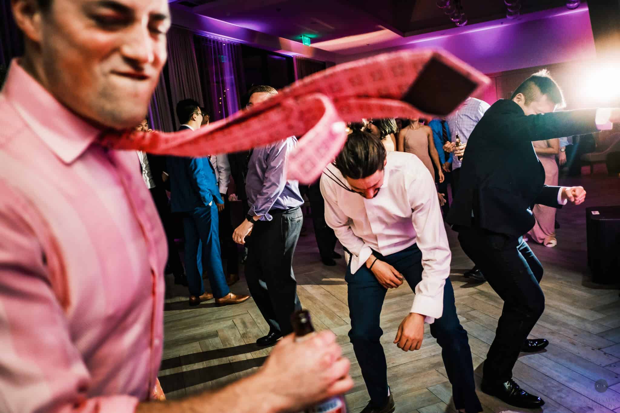 Wedding guests dance vigorously to DJ music.