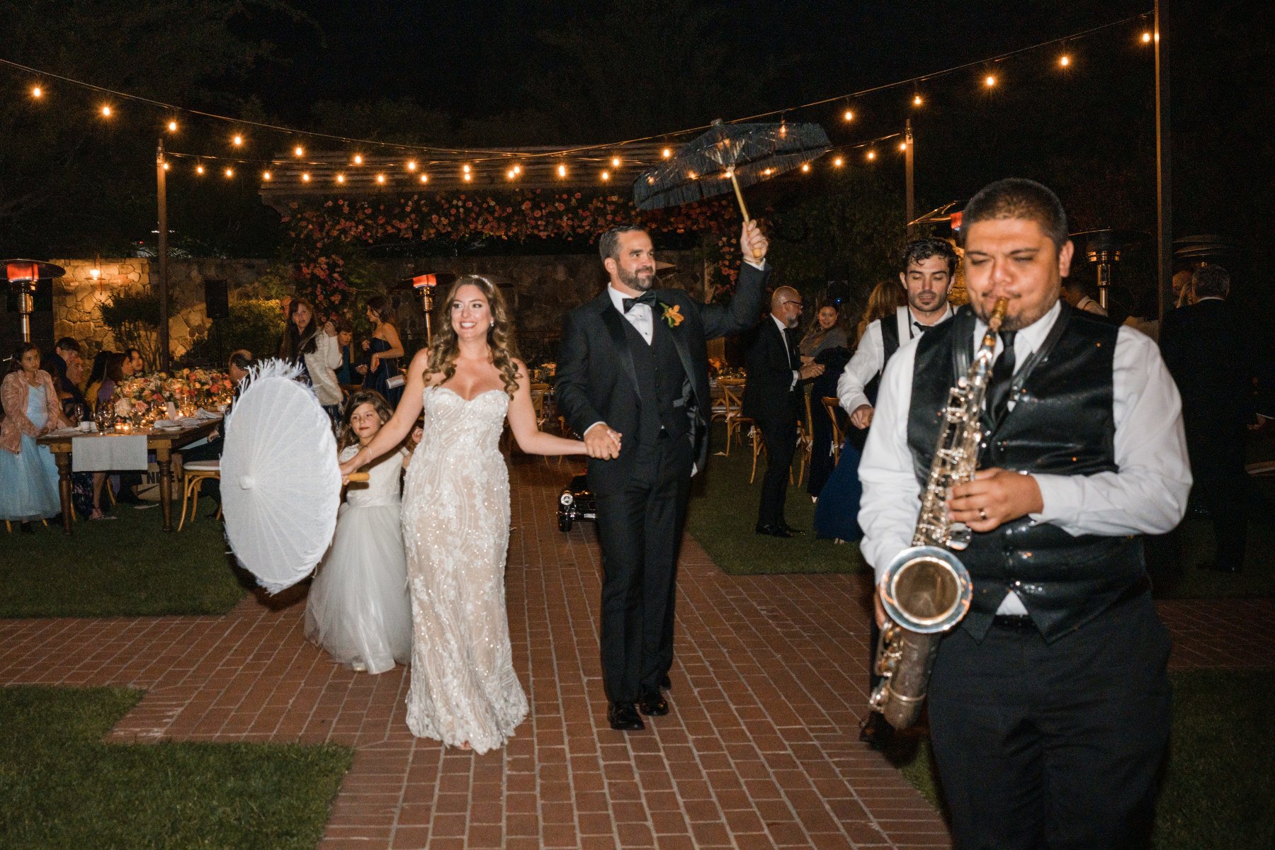 A celebration at the Yountville Wedding Venue shows a bride and groom celebrating New Orleans style with a band playing a saxophone. ,Wedding planned by Blissful Events. Photo by Lily Rose.