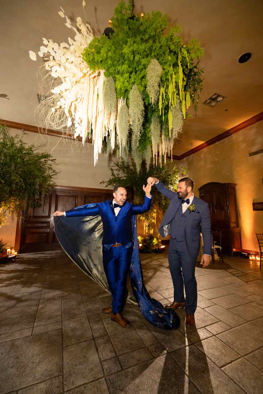 A newly married couple share a first dance on the dance floor at Clos La Chance Winery. Trees and floral arrangements by Bella Vita Floral Productions. Wedding by Blissful Events. Image Captured by Danny Dong Photography.