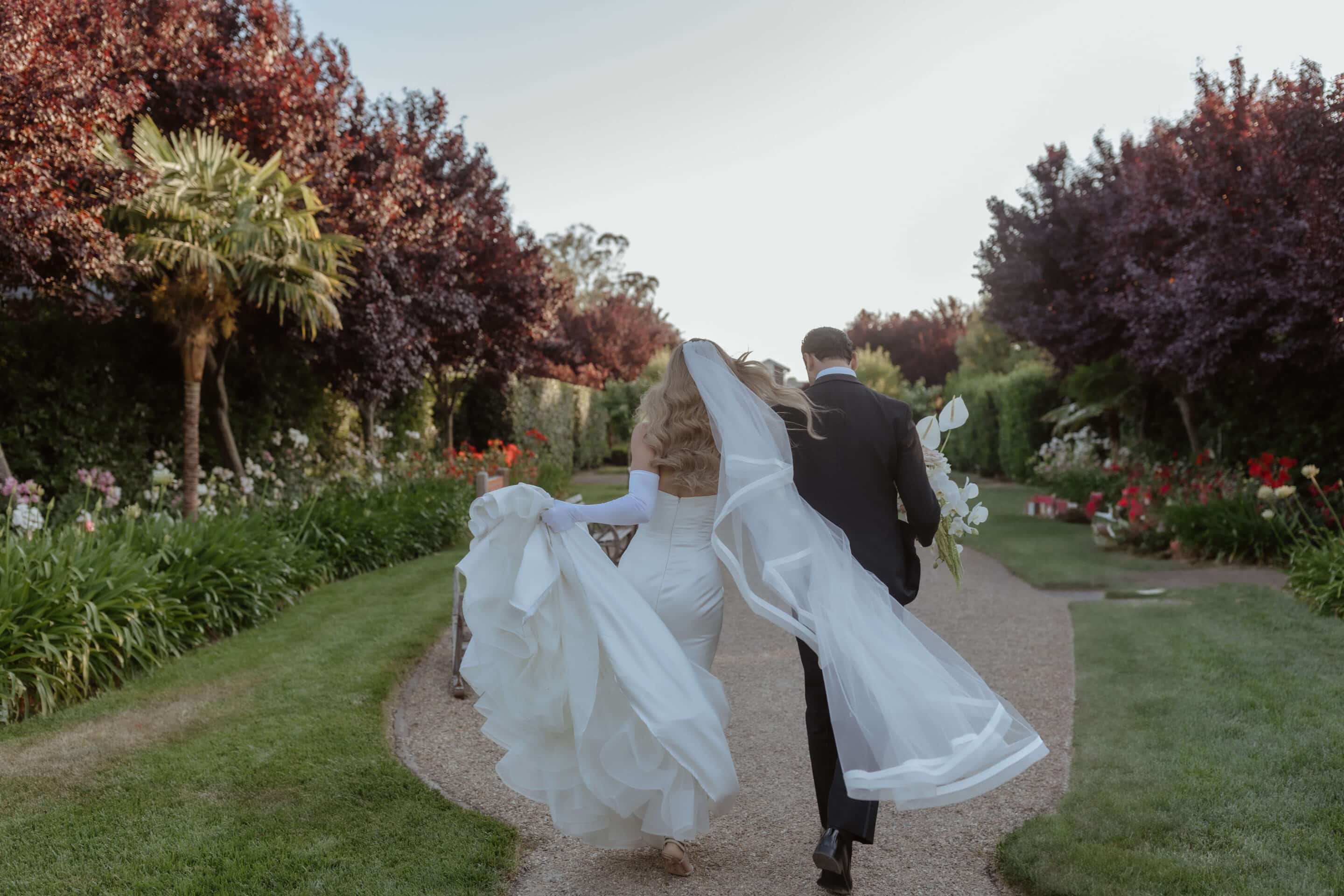 Bella Vita Floral Productions created the stunning bouquet the groom is carrying as the newly married couple walk away into the sunset. Photo by Andrea Lowry Photography. Wedding by Blissful Events.